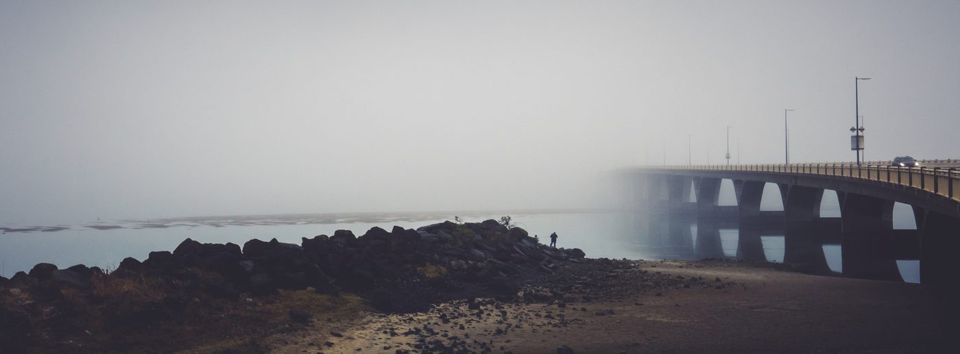 Foggy bridge over water.