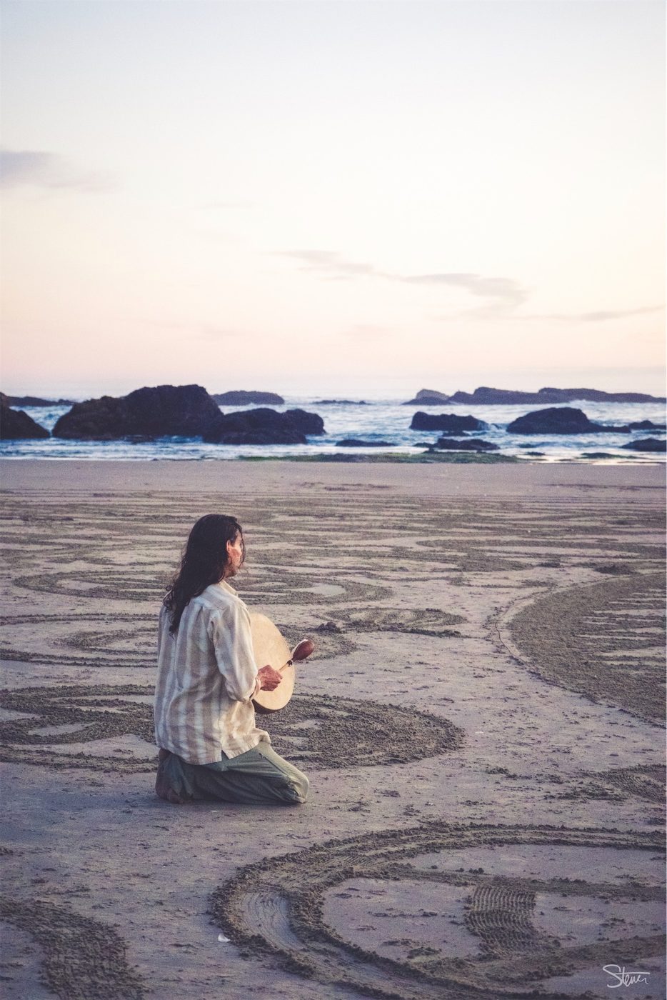 Man Playing Instrument On Beach.
